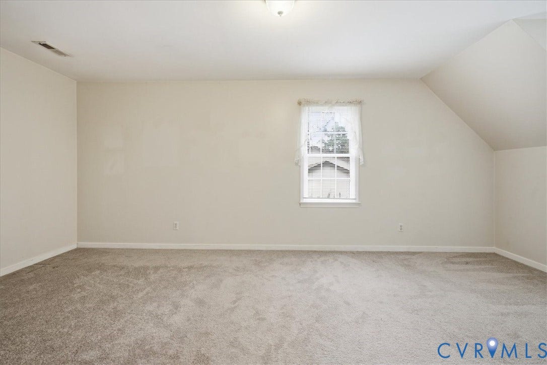 13308 S Chester Road, Chester, VA 23831 Spacious upper-level bedroom featuring neutral carpeting, angled vaulted ceilings, and a single-hung window with natural light exposure