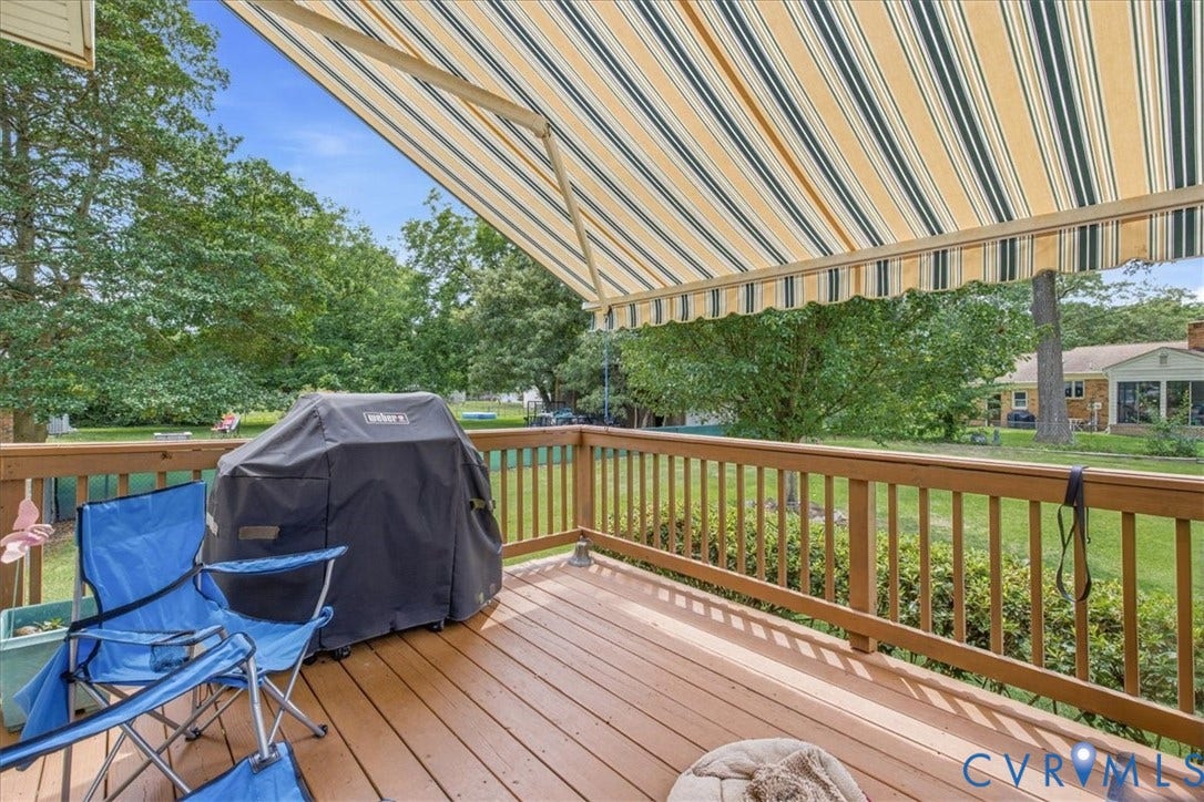 13308 S Chester Road, Chester, VA 23831 Spacious composite deck featuring warm wood-finish decking, a sturdy wood railing system, and a retractable striped awning providing shade coverage