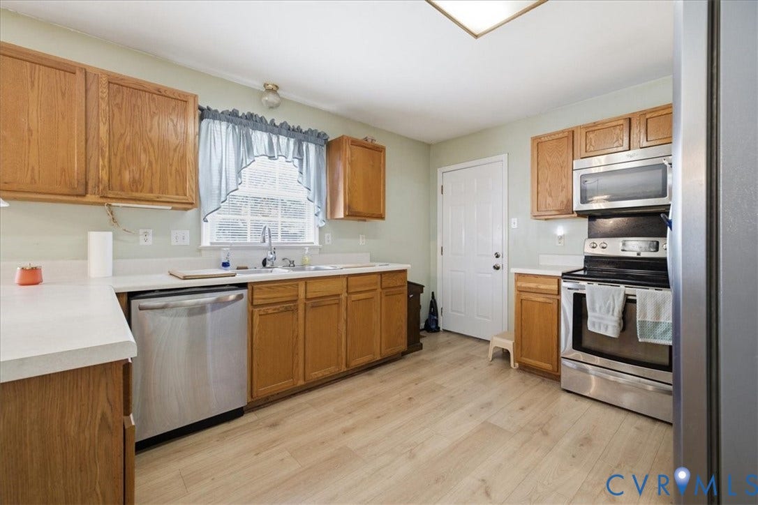 13308 S Chester Road, Chester, VA 23831 Spacious kitchen featuring warm wood cabinetry, stainless steel appliances including double wall ovens, a dishwasher, and a generous island with seating