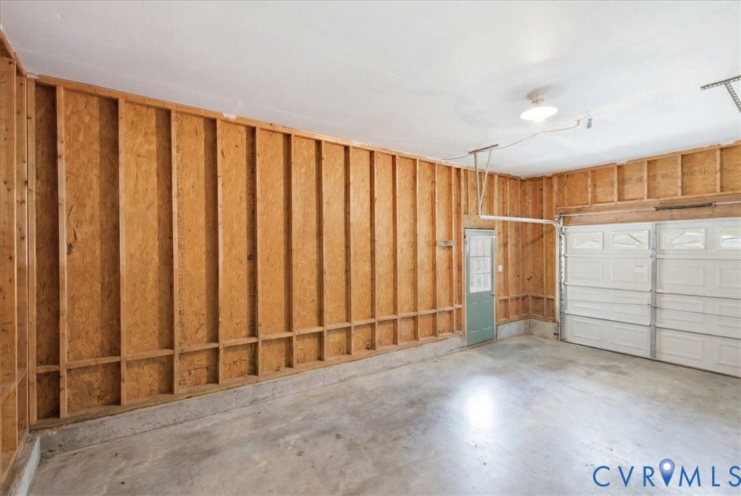 13308 S Chester Road, Chester, VA 23831 Spacious two-car garage featuring exposed wood-framed construction, concrete flooring, and dual overhead doors with natural light from windows