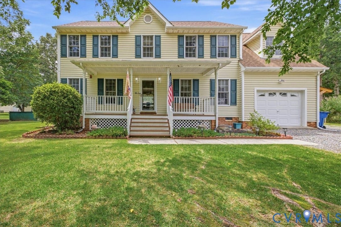 13308 S Chester Road, Chester, VA 23831 Classic two-story Colonial with welcoming front porch featuring lattice detailing and columns, cream-colored vinyl siding, black shutters and trim, attached two-car garage, and manicured lawn with mature landscaping and established shade trees