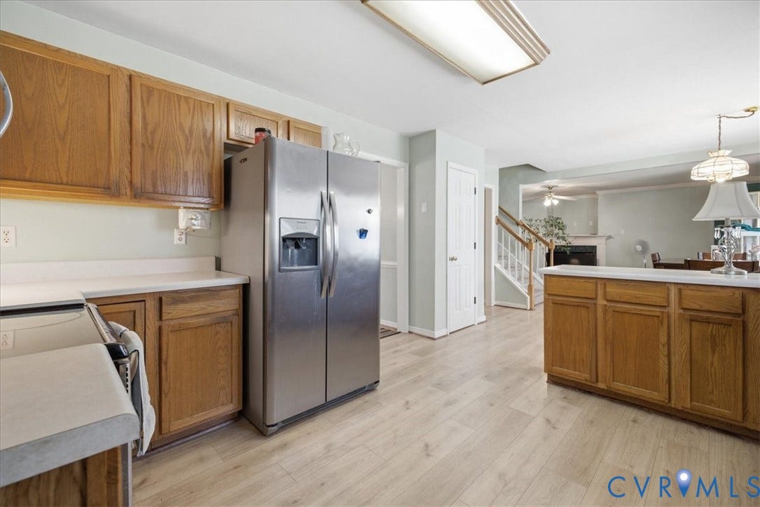 13308 S Chester Road, Chester, VA 23831 Spacious kitchen featuring stainless steel side-by-side refrigerator with ice and water dispensers, wood cabinetry throughout, light wood-finish flooring, and ample counter space