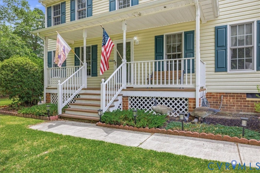 13308 S Chester Road, Chester, VA 23831 Welcoming front porch featuring white painted railings, brick foundation with lattice skirting, concrete walkway, and wide wooden steps with brown-finish trim