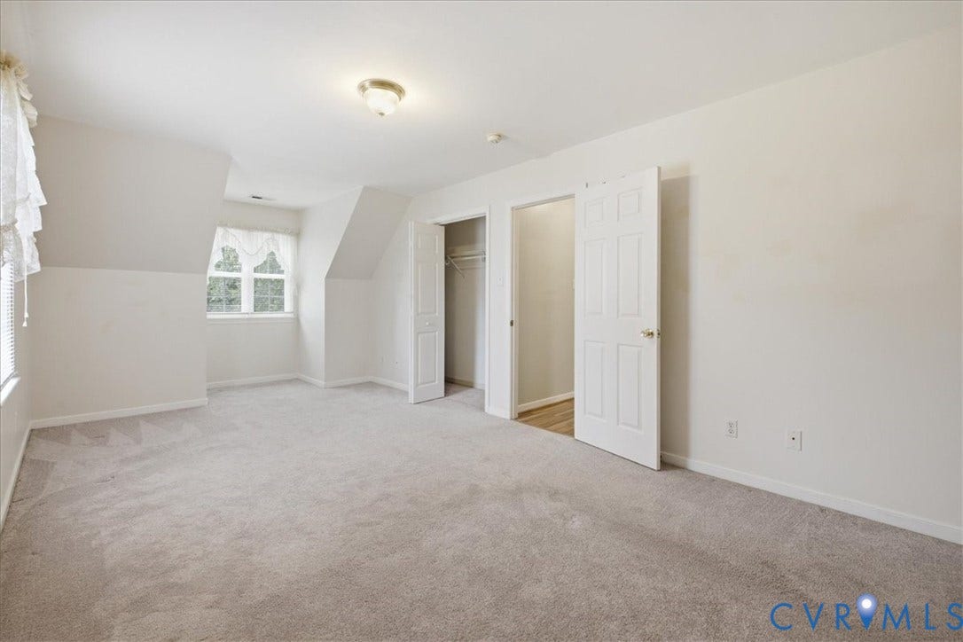 13308 S Chester Road, Chester, VA 23831 Spacious upper-level bedroom with vaulted ceilings, abundant natural light from a dormer window, neutral carpeting, and multiple closet spaces with white six-panel doors