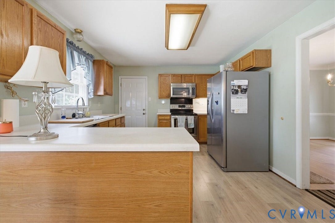 13308 S Chester Road, Chester, VA 23831 Spacious kitchen featuring wood cabinetry, stainless steel appliances including a side-by-side refrigerator and built-in microwave, white quartz countertops, a large island with wood-finish base, wood-finish flooring throughout, and recessed ceiling lighting