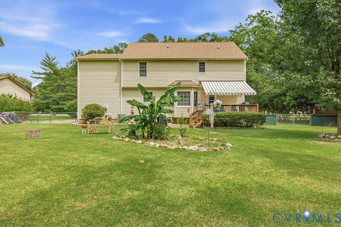 13308 S Chester Road, Chester, VA 23831 Spacious backyard featuring a manicured lawn, mature landscaping with tropical plantings, and established shade trees