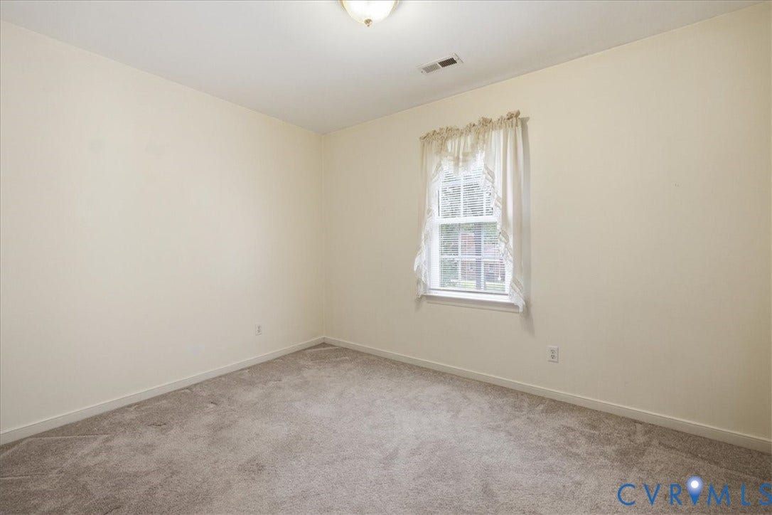 13308 S Chester Road, Chester, VA 23831 Bright, naturally lit bedroom featuring neutral wall finishes, carpet flooring, and a single-hung window with sheer drapery