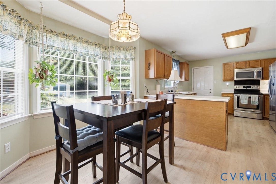13308 S Chester Road, Chester, VA 23831 Kitchen featuring wood-finish flooring, light wood cabinetry, stainless steel appliances, and a built-in island