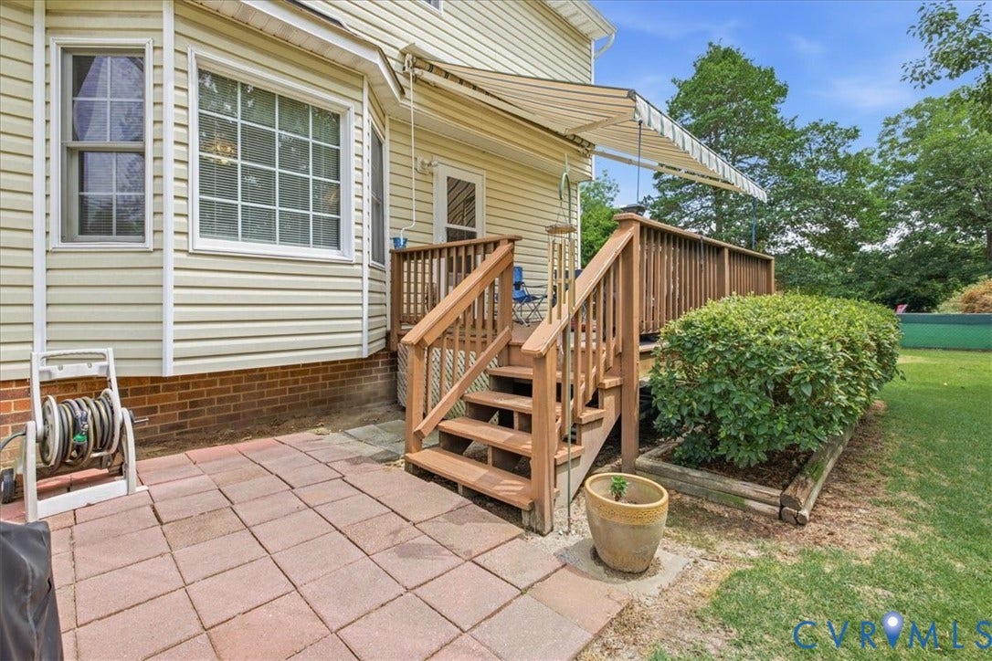 13308 S Chester Road, Chester, VA 23831 Spacious composite patio featuring brick pavers, wooden deck with railings and multiple steps, retractable awning, and direct access to the home's exterior
