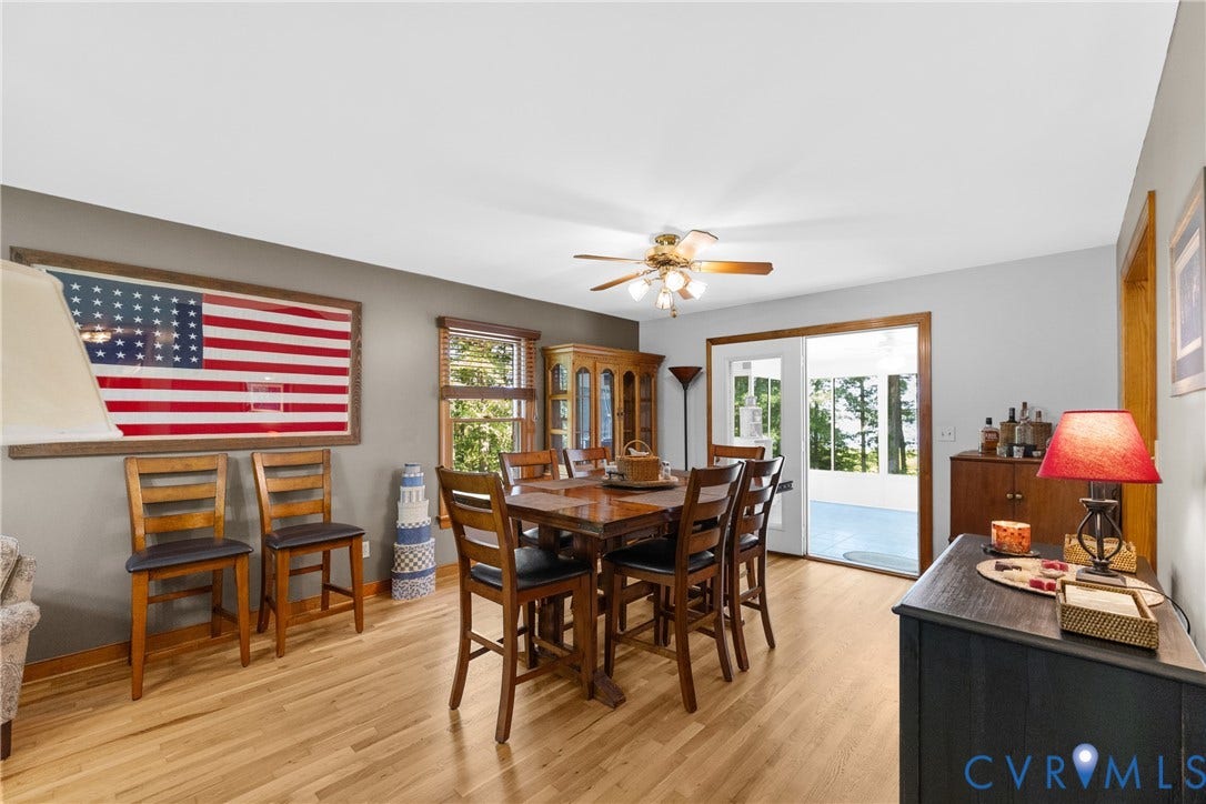 3621 Jefferson Highway, Rual, Mineral, VA 23093 Bright dining area showcasing warm wood-finish flooring, a solid wood dining table with ladder-back chairs, and abundant natural light from multi-pane windows and glass doors