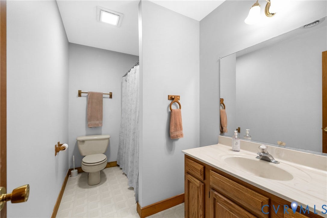 3621 Jefferson Highway, Rual, Mineral, VA 23093 Oak wood-finish vanity with an integrated sink, polished chrome faucet, and a large wall-mounted mirror