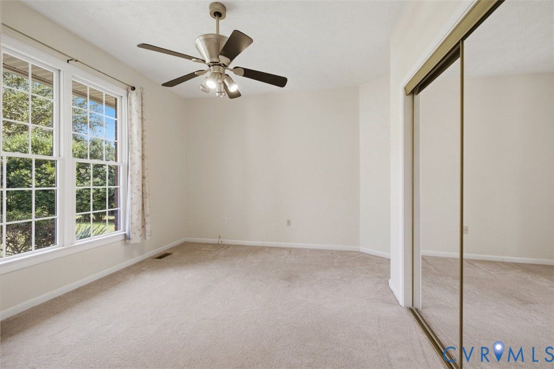 12600 Lilking Road, Chester, VA 23831 Spacious bedroom flooded with natural light through expansive multi-pane windows, neutral carpet flooring, ceiling fan with integrated lighting, and mirrored sliding-door closet system providing ample storage