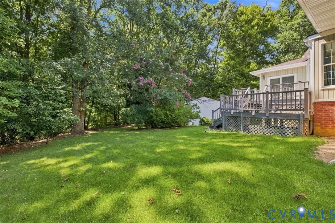 12600 Lilking Road, Chester, VA 23831 Expansive backyard featuring a manicured lawn, mature tree canopy providing natural shade, and a brick exterior home with an elevated composite deck and lattice railing