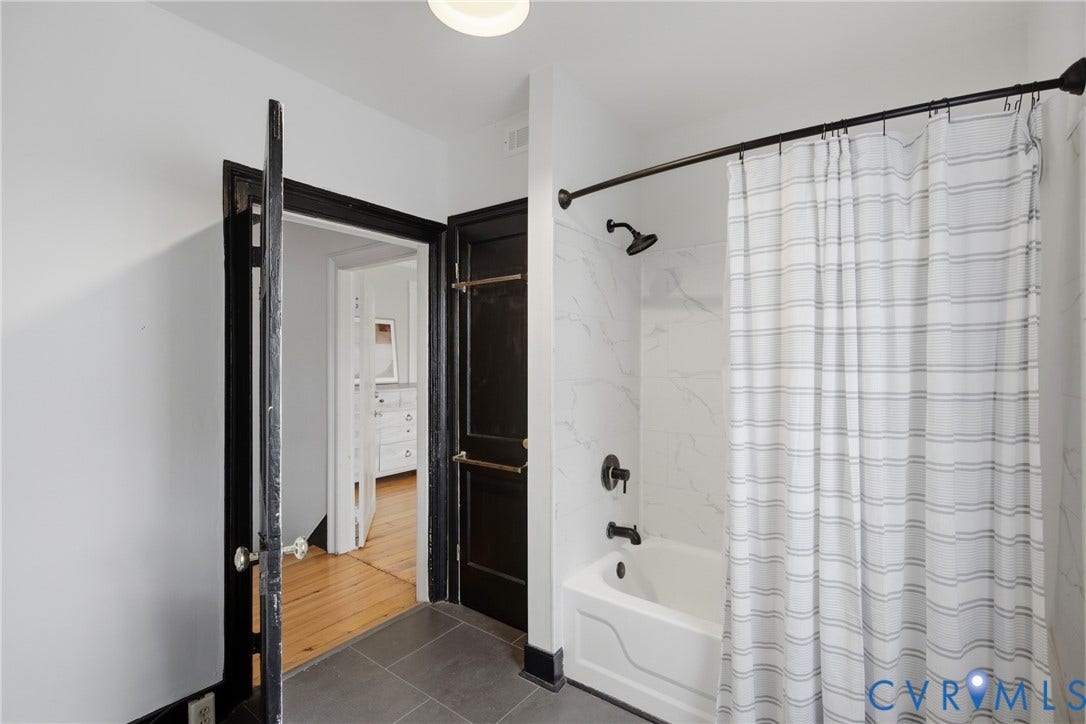 209 W Clay Street, Jackson Ward, Richmond, VA 23220 Tub and shower combination with dark bronze fixtures, white subway tile surround, and gray tile flooring