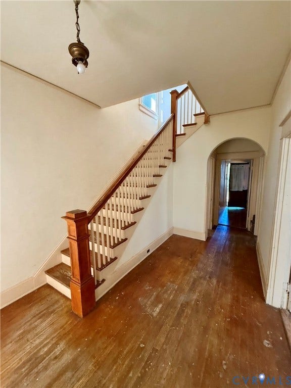 1313 Enfield Avenue, Richmond, VA 23224 Hardwood flooring, wood staircase with white balusters, wood newel post, arched doorway, and a ceiling-mounted light fixture