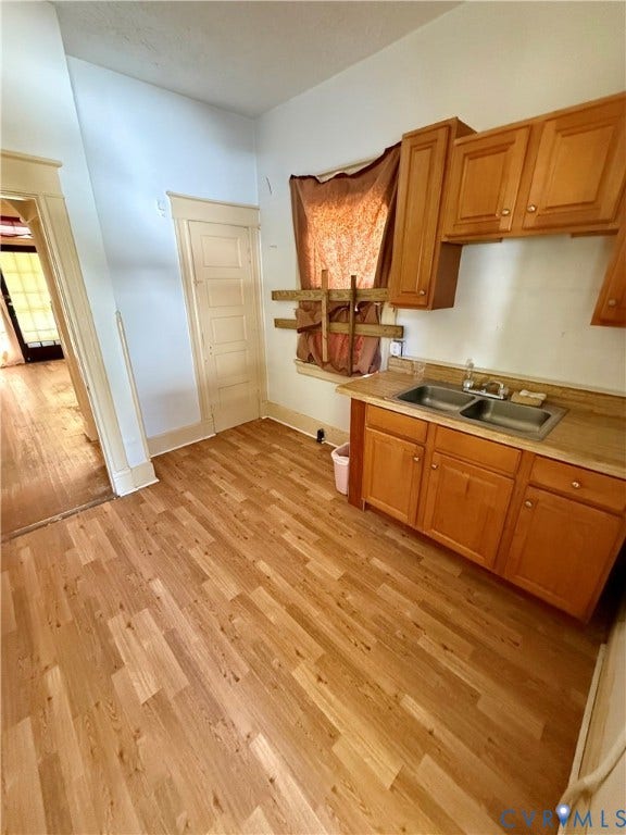 1313 Enfield Avenue, Richmond, VA 23224 Wood-finish flooring throughout, paired with a double-basin stainless steel sink, and wood cabinetry with coordinating upper and lower units