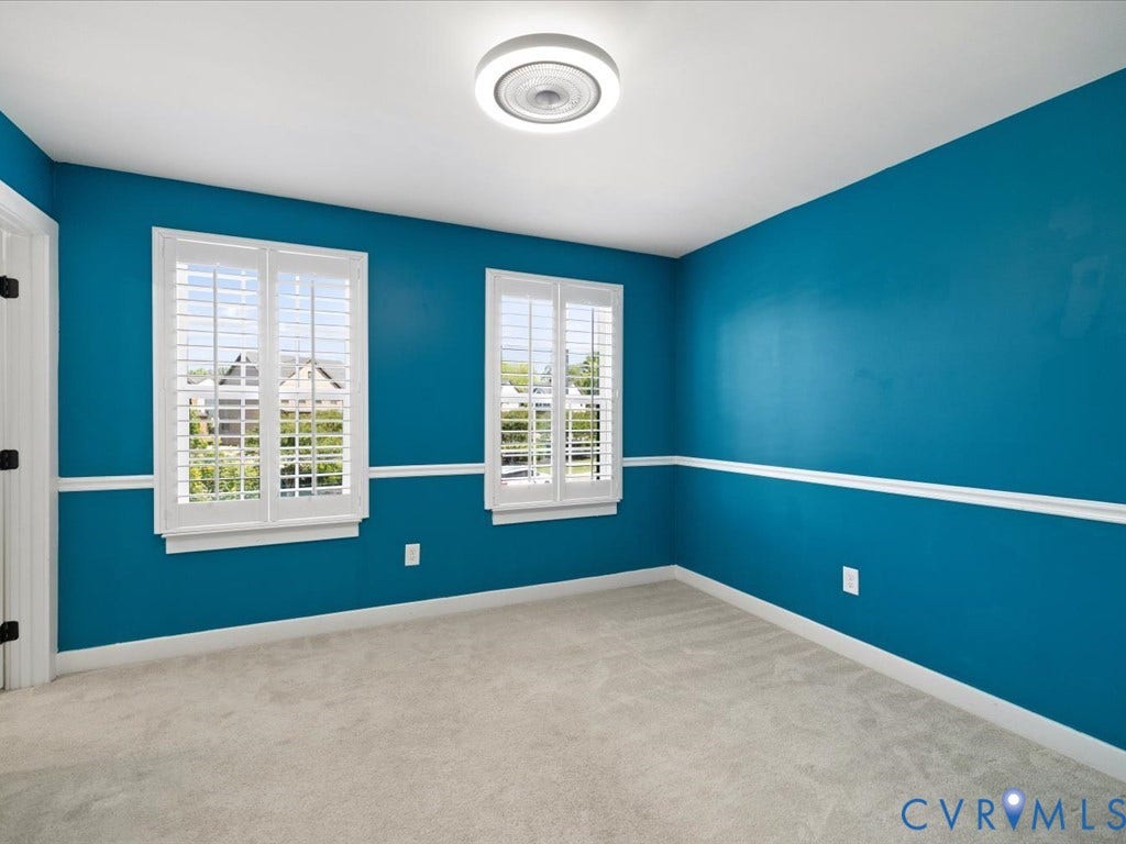 Plush carpeting, two windows with plantation shutters, decorative chair rail molding, and a flush mount ceiling light fixture