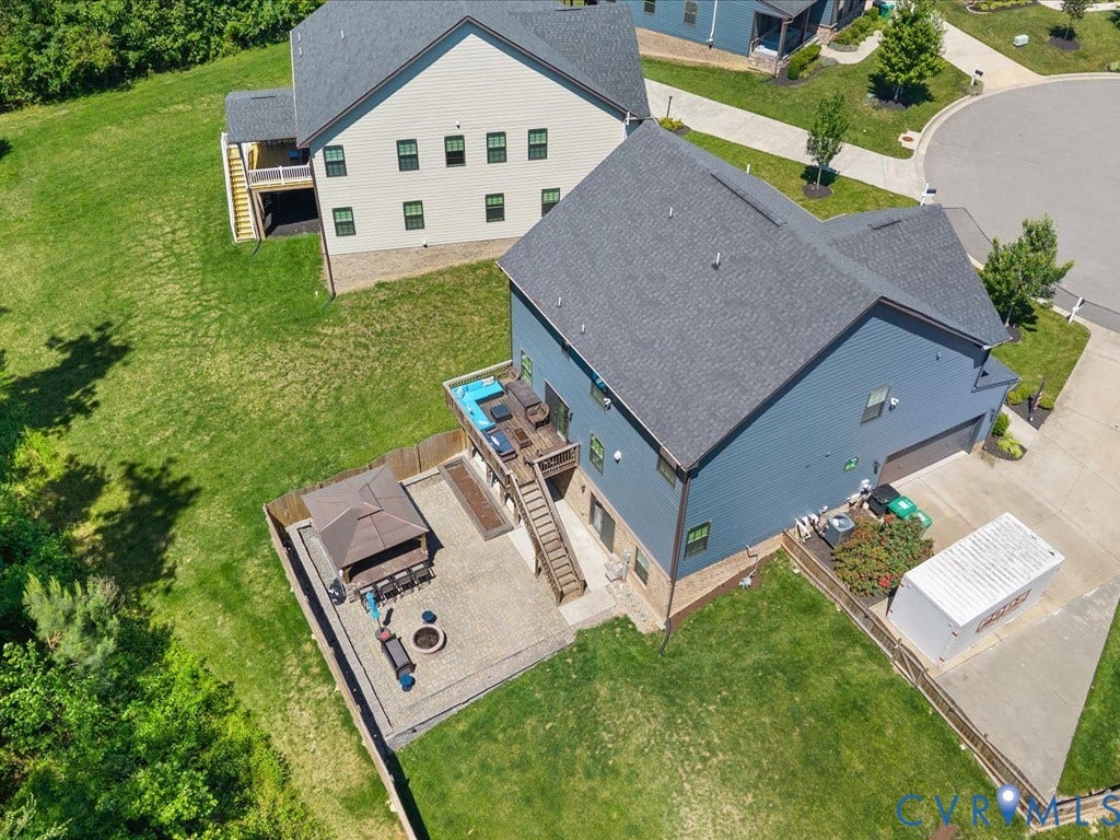Rear exterior featuring an elevated wood deck, a ground-level paver patio, and a fenced yard