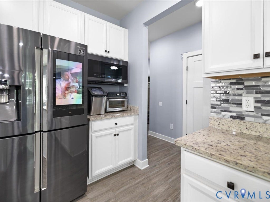 White shaker-style cabinetry, light-toned granite countertops, and a mosaic tile backsplash