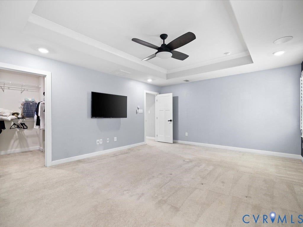 Recessed lighting, tray ceiling, ceiling fan, wall-to-wall carpeting, and an open closet