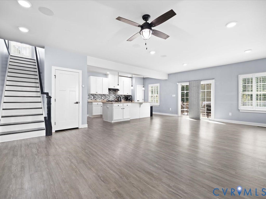 Wood-finish flooring throughout, white kitchen cabinetry with backsplash, ceiling fan, recessed lighting, and patio doors