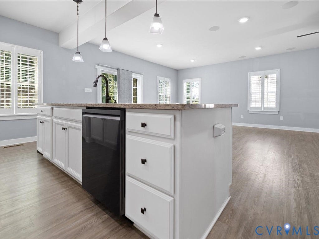 Kitchen island with white cabinetry, a built-in dishwasher, and a stone-look countertop