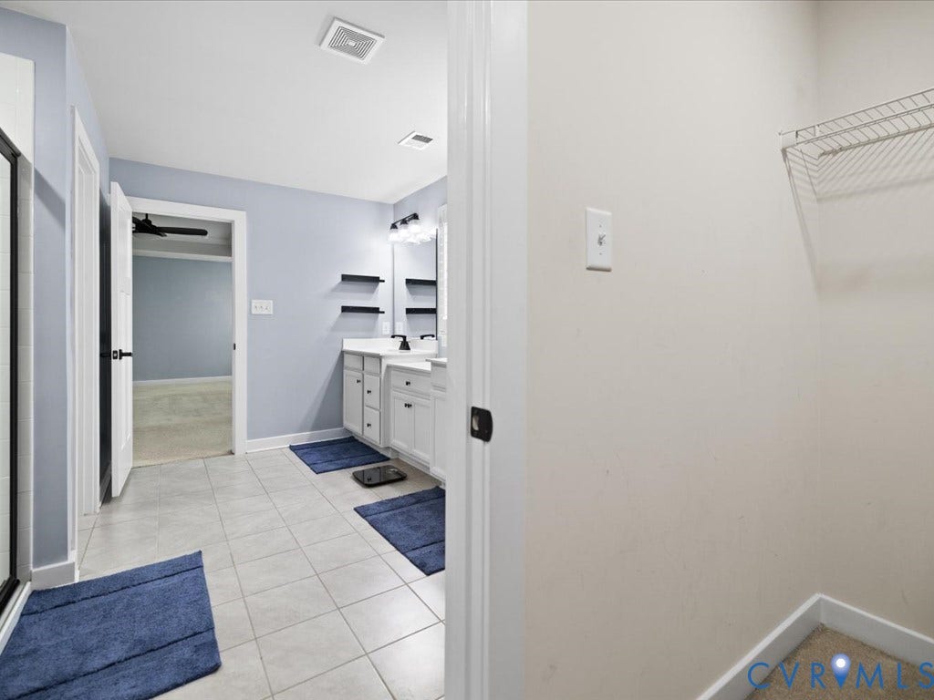 Bathroom with dual vanity, white cabinetry, integrated sinks, and tile flooring