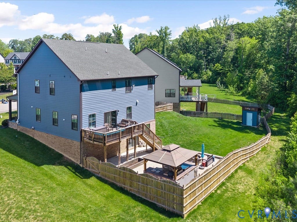 Rear exterior with blue siding, multi-level wood deck, a fenced yard, and a separate patio area