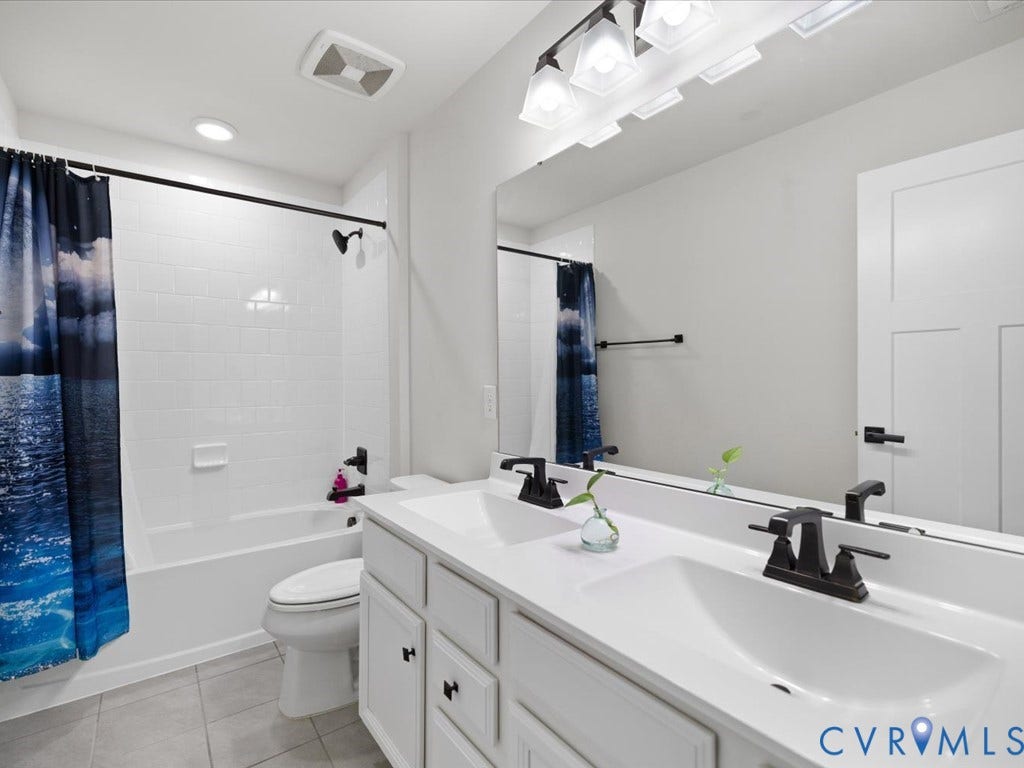 Dual basin vanity with white cabinetry and dark hardware