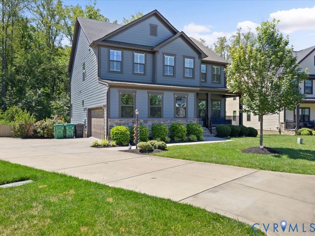 Two-story residence featuring a covered front porch, stone and siding exterior, attached garage, and concrete driveway
