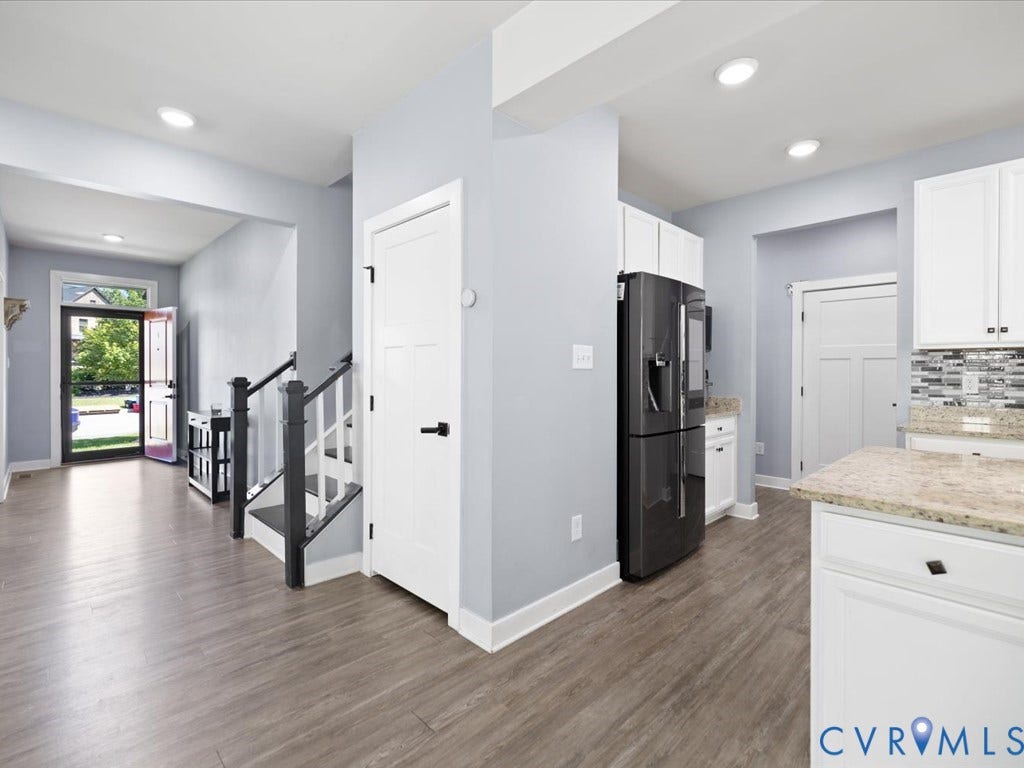Wood-finish flooring throughout, white cabinetry with dark hardware, stone countertops, and recessed lighting