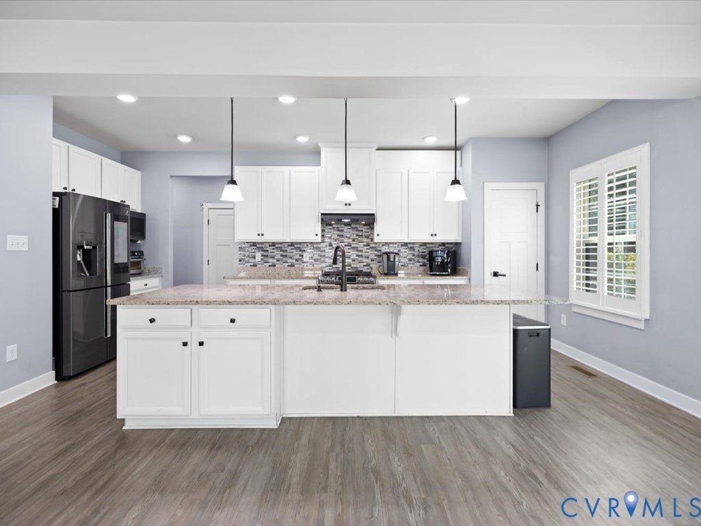 White cabinetry with black hardware, granite countertops, tile backsplash, wood-finish flooring, and recessed and pendant lighting
