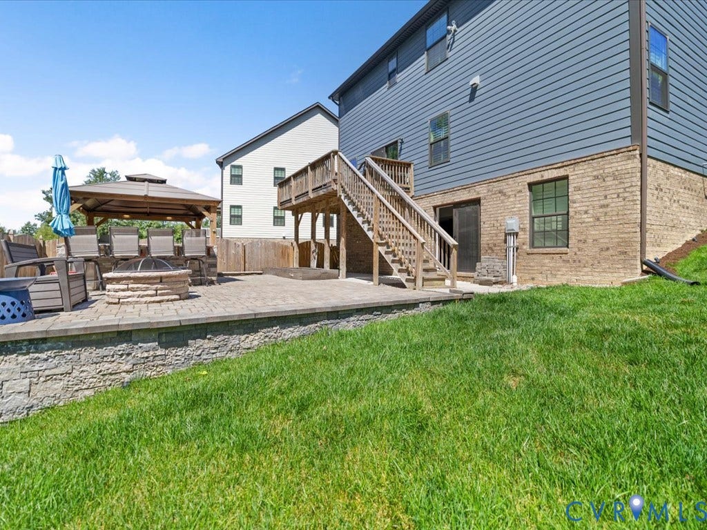 Expansive outdoor patio featuring paver stones, a stone-finish fire pit, and a built-in gazebo structure