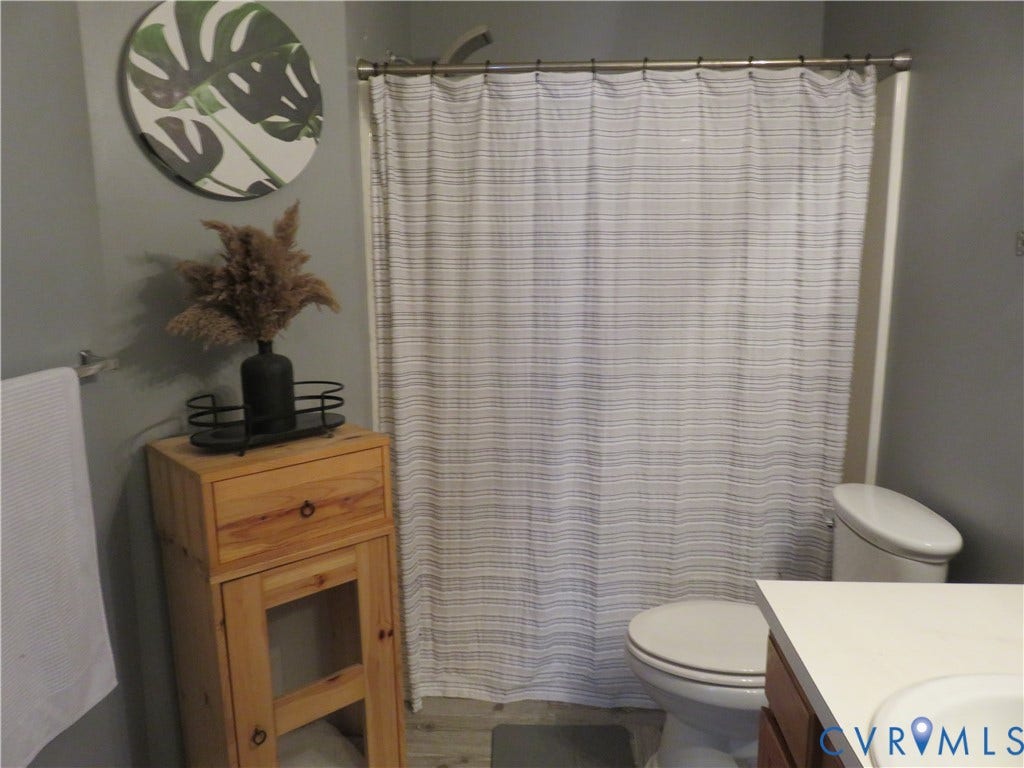 3107 McCabe Court, Chester, VA 23831 Upstairs Bathroom featuring a shower with a white surround, a white toilet, and a wood-finish storage cabinet with a drawer