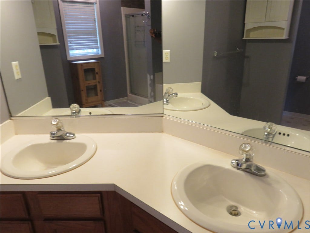 3107 McCabe Court, Chester, VA 23831 Dual undermount sinks set within a light-toned countertop, large wall-mounted mirrors, and wood-finish cabinetry