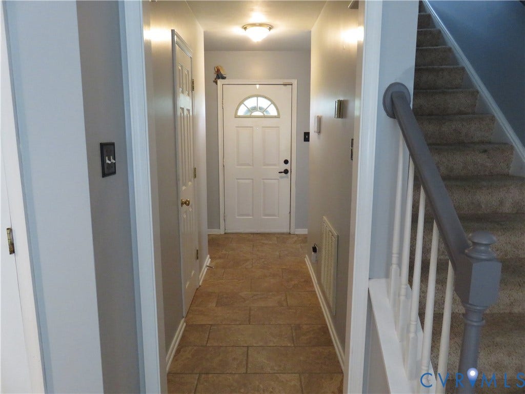 3107 McCabe Court, Chester, VA 23831 Entryway featuring rectangular tile flooring, a white paneled door with an arched window, and a carpeted staircase with a painted banister