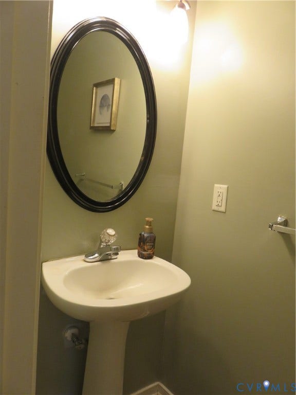 3107 McCabe Court, Chester, VA 23831 Pedestal sink with a single-handle faucet, oval wall mirror, and wall-mounted vanity lighting