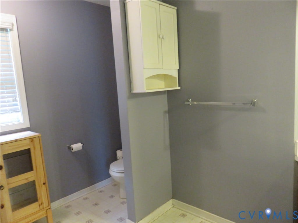 3107 McCabe Court, Chester, VA 23831 Built-in wall cabinetry, window with white blinds, wall-mounted towel bar, and patterned floor tile