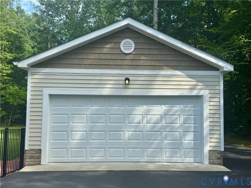 17225 Ivory Bill LANE, Chesterfield, VA 23838 Single-car garage with a paneled door, horizontal siding, and a gable roof with shingle-style siding