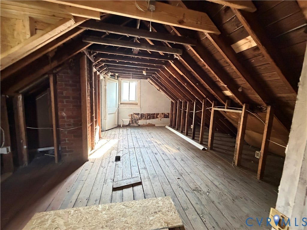 3911 Larchmont Lane, Richmond, VA 23224 Exposed rafters, brick wall accent, wood plank flooring, and a casement window
