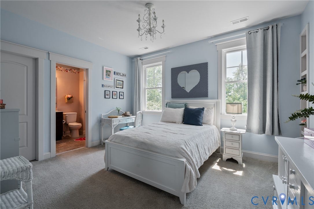 Recessed lighting with a crystal chandelier, two double-hung windows, and light blue walls