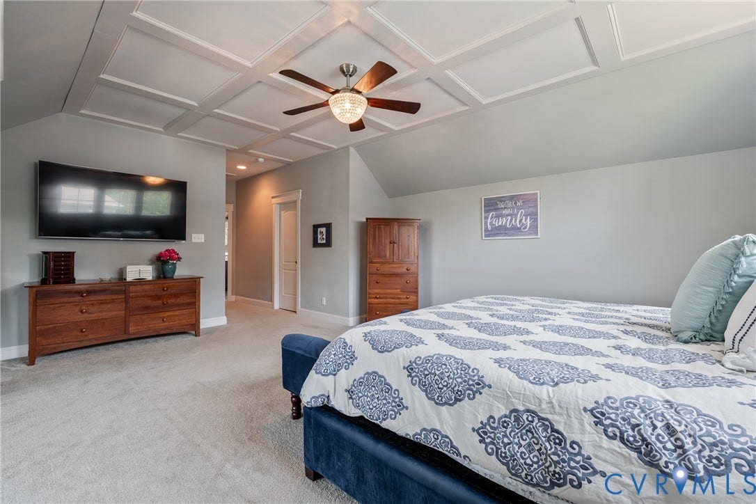 Coffered ceiling with a ceiling fan light fixture, light gray wall paint, and light-colored carpeting