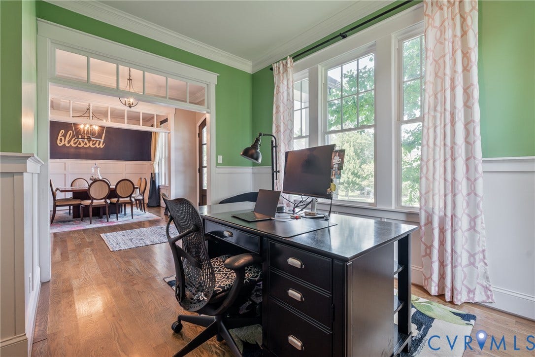 Hardwood flooring, wainscoting, green painted walls, white trim, and a wide cased opening