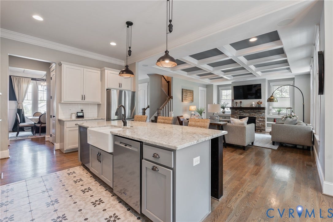 Kitchen island with a farmhouse sink, stainless steel appliances, wood-finish flooring, white cabinetry, and a coffered ceiling