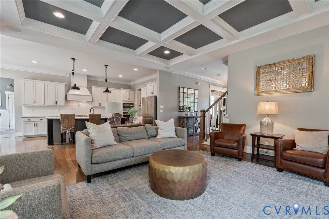 Coffered ceiling with recessed lighting, wood-finish flooring, white cabinetry, kitchen island with seating, and a stainless steel refrigerator