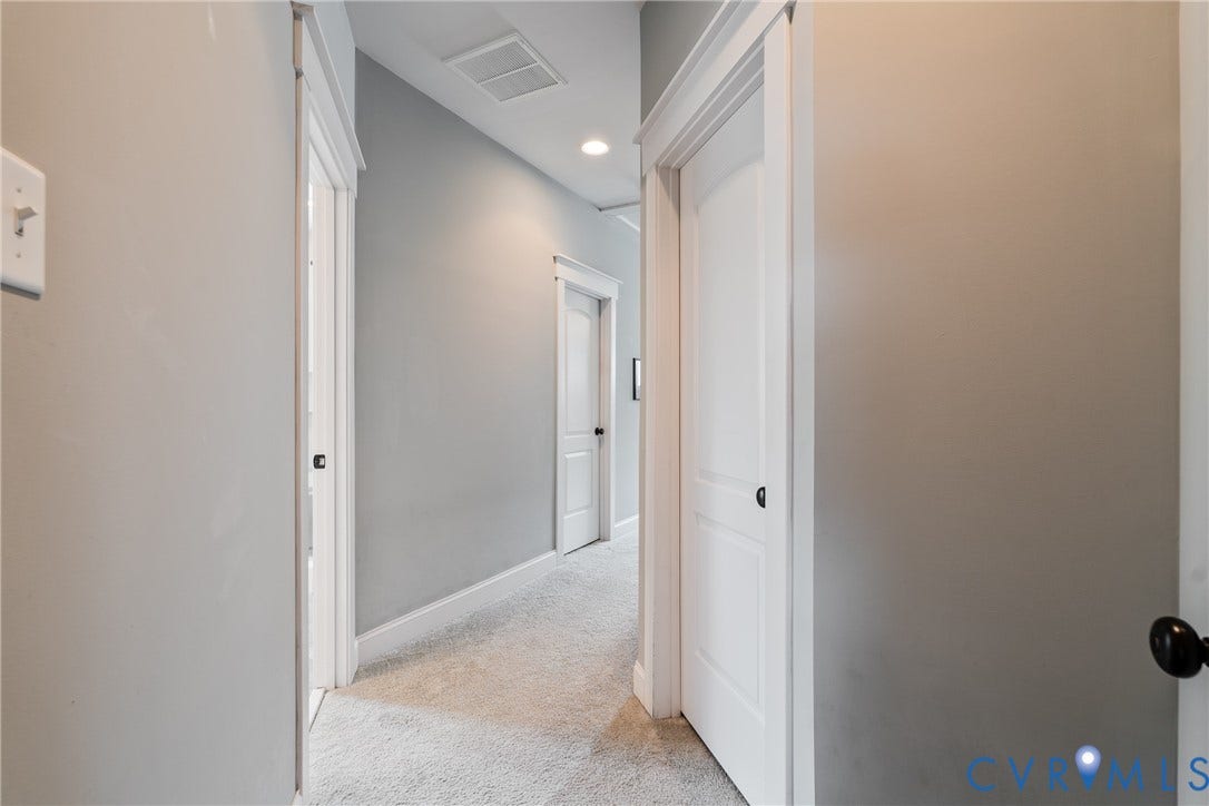 Carpeted hallway with light gray walls, white trim, and recessed lighting