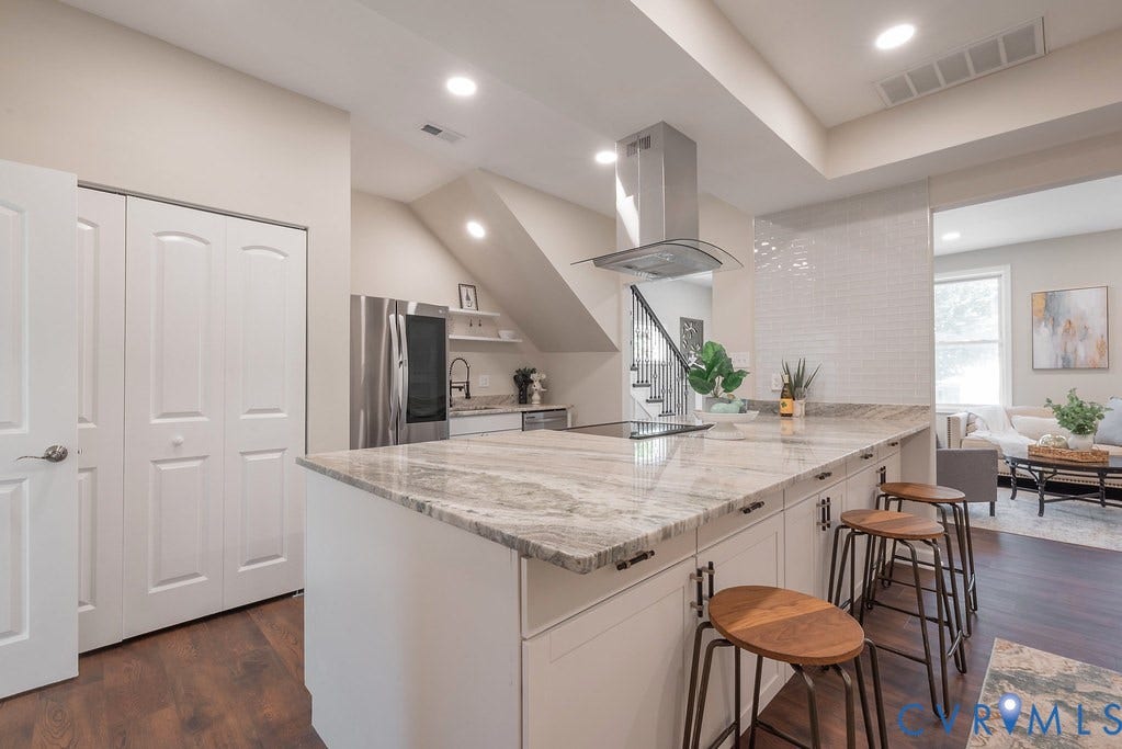 Kitchen featuring an expansive island with a stone countertop, built-in cooktop, and a stainless steel range hood