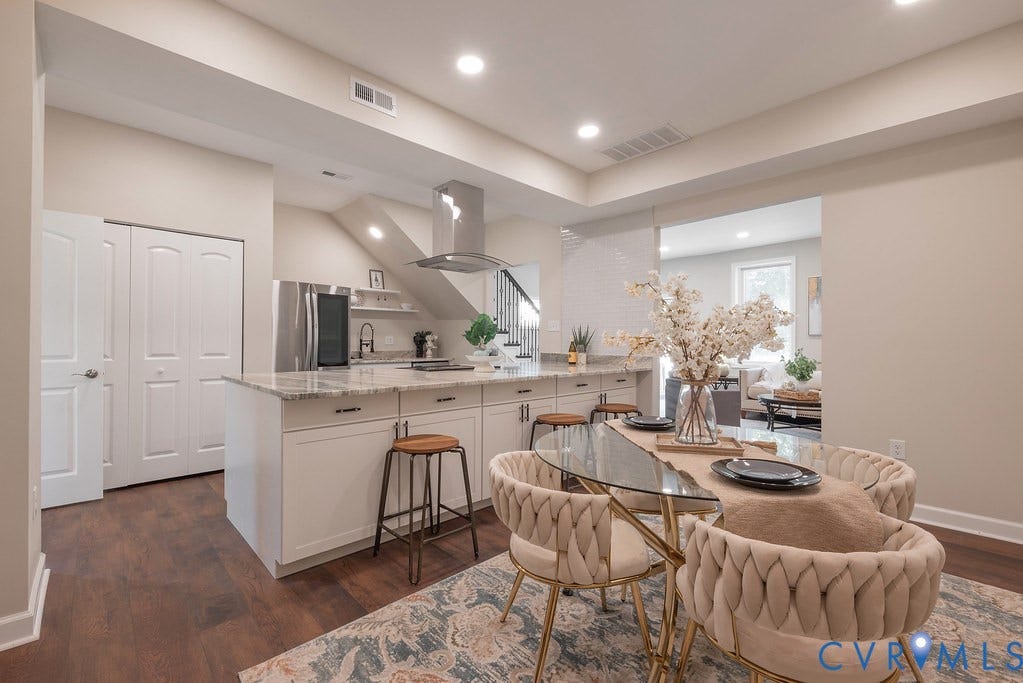 Open-concept kitchen and dining area featuring wood-finish flooring, recessed lighting, white cabinetry, and granite countertops