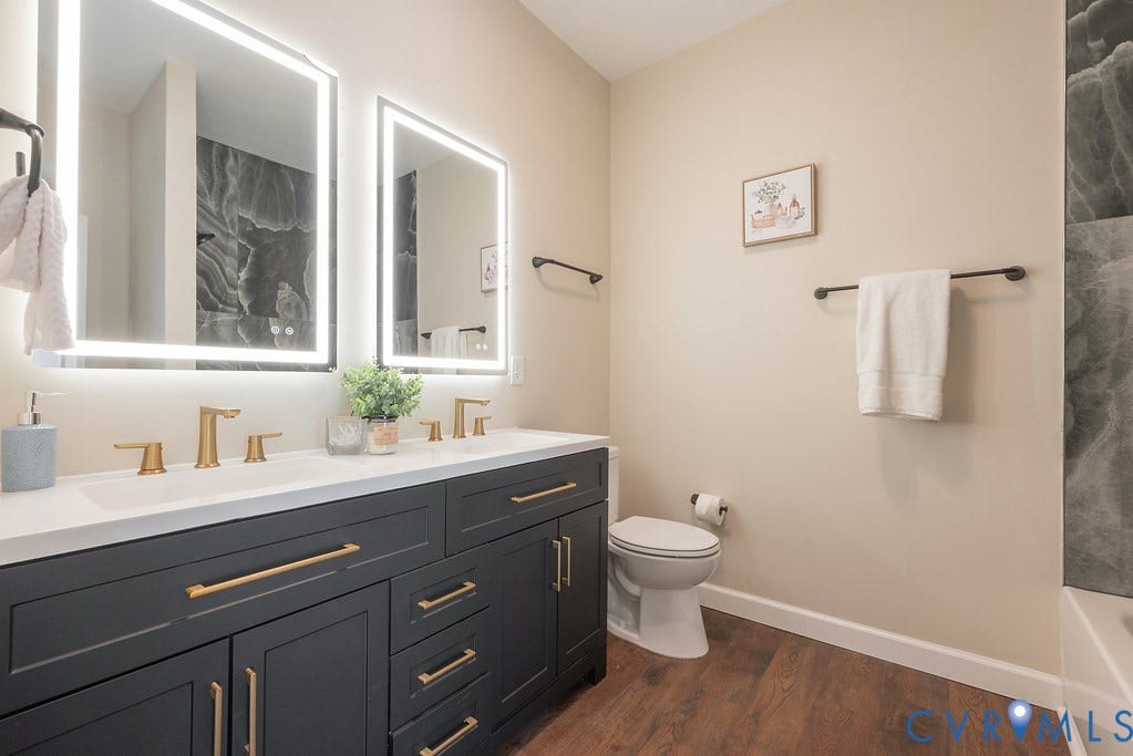 Dual vanity with dark cabinetry, gold-finish hardware, and integrated rectangular sinks