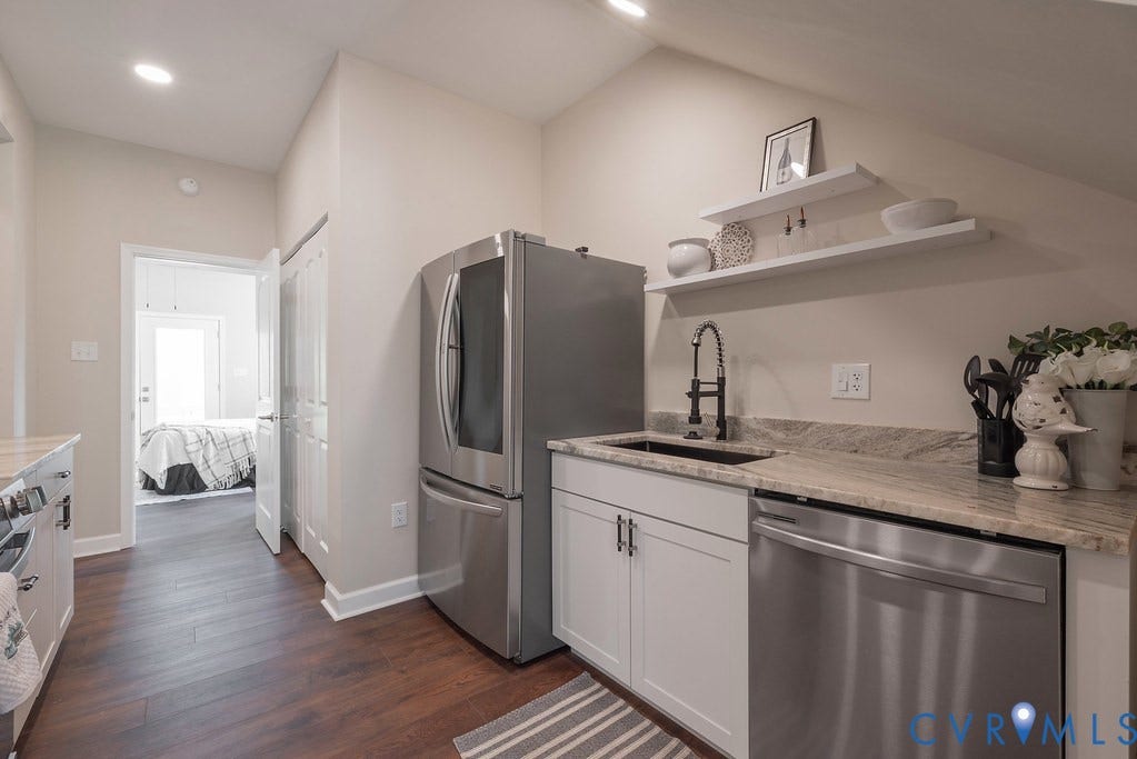 Stainless steel refrigerator, stainless steel dishwasher, wood-finish flooring, white cabinetry, and granite countertops